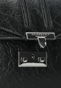 Sac à main en cuir noir avec une surface texturée, doté de quincaillerie argentée, d'une fermeture à verrou et d'un logo en relief sur le devant.