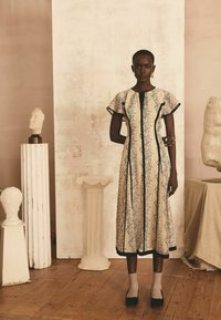 Blumenmuster Midi-Kleid in Creme und Schwarz mit kurzen Ärmeln. Verfügt über vertikale Nahtlinien, einen Frontreißverschluss und kontrastierende schwarze Akzente.