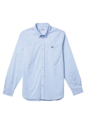 Chemise à manches longues bleu clair en coton, dotée d'un col pointu et d'un petit logo vert sur la poitrine gauche.