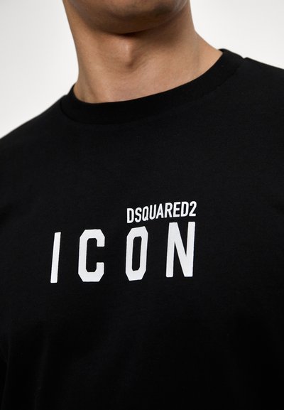 Sort bomulds T-shirt med rund hals, korte ærmer og en hvid trykt etikette med teksten "DSQUARED2 ICON." Klassisk pasform og glat tekstur.