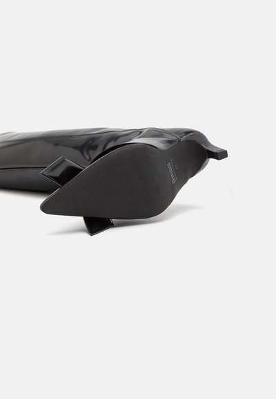 Stivaletto nero con punta a punta, finitura lucida, materiale flessibile e tacco corto a blocco con dettagli a fiocco sul retro.