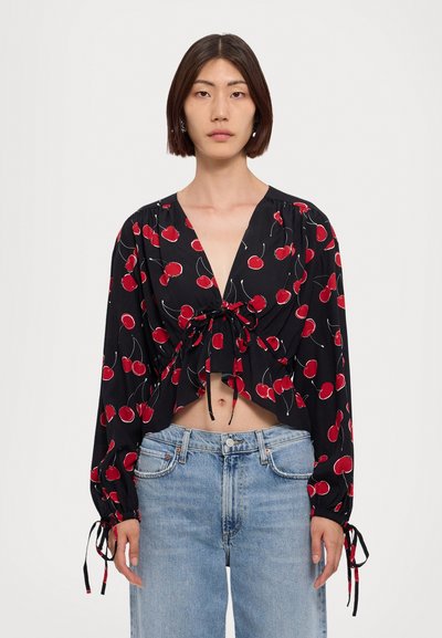 Blusa nera cropped con motivo di ciliegie rosse, scollatura a V profonda, maniche lunghe e lacci regolabili in vita e ai polsini, realizzata in tessuto leggero.