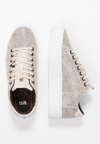 Baskets beiges à surface texturée, semelle en caoutchouc blanche et bout rond. Équipées de lacets à l'avant et d'une doublure intérieure noire avec logo.