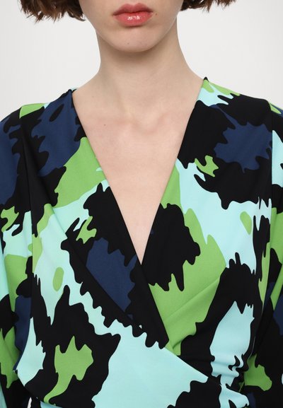 Rochie înfășurată colorată cu un model de forme abstracte negre, verzi și albastre, cu un decolteu adânc în V și o textură a țesăturii netedă.