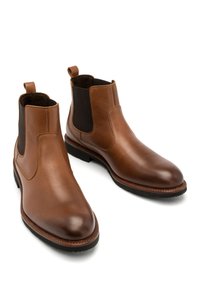 Brązowe skórzane botki za kostkę z elastycznymi panelami bocznymi, zaokrąglonym czubkiem oraz teksturowaną podszewką wewnętrzną. Posiadają pętle ułatwiające zakładanie.