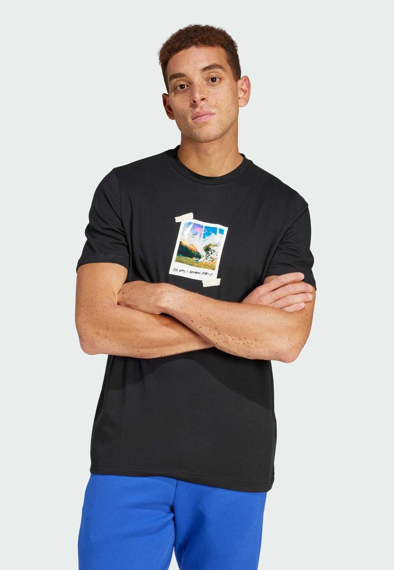 T-shirt en coton noir avec un graphique coloré de paysage montagneux encadré de ruban sur le devant. Design col rond. Manches courtes sans couture.