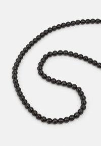 Svart perlekjede med jevnt fordelte, matte perler, arrangert i en fleksibel, buet form. Glatt tekstur, minimalistisk design.