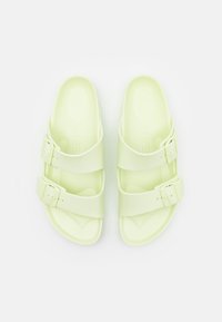 Sandales vert clair avec deux sangles réglables et boucles. Fabriquées en matériau lisse, avec une semelle intérieure ergonomique et une forme arrondie.