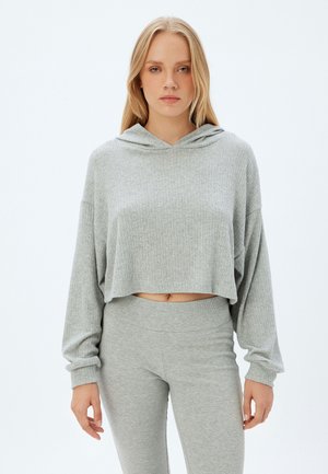 Gekürzter grauer Hoodie aus strukturiertem, geripptem Material mit einer Kapuze mit Kordelzug, kombiniert mit passenden grauen Leggings. Einfaches, klares Design.