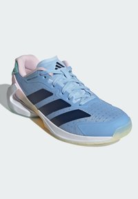 Light blue athletic shoe with navy stripes, mesh upper, rounded toe, and cushioned sole. Features pastel pink accents on the heel.