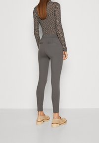 Grå leggings med hög midja och bakfickor, i kombination med en randig långärmad topp och ljusa plattformsskor.