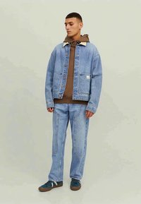 Light blue denim jacket with tan collar, paired with matching light blue denim pants. The outfit features a brown hoodie underneath.