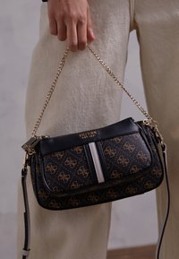 Czarna i brązowa torebka na ramię w wzór, z łańcuszkowym paskiem, wyposażona w zamek błyskawiczny, złotymi akcentami i białym paskiem wzdłuż.