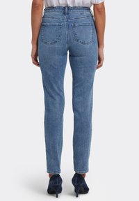 Faded blå jeans i denim med en figurnära design, hög midja och fem fickor. Har subtila slitningar och raka ben.