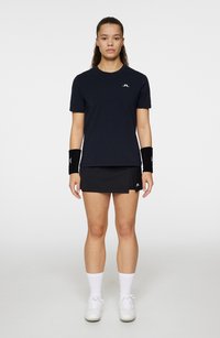 Svart kortärmad träningströja med rund halsringning, kombinerad med en svart kjol. Inkluderar vita handledsstöd och vita strumpor med gympaskor.