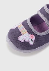 Lila tygskor med en unicorn-design. Har en mjuk textur, två justerbara remmar och en genomskinlig sula med glittrande detaljer.