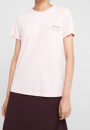 Light pink short-sleeve t-shirt made from recycled cotton, featuring a text print on the left chest area. Soft, casual material.