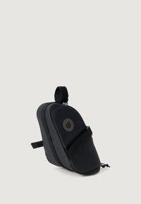 Melna mugursoma, kas izgatavota no izturīga auduma, ar izliekta dizaina, regulējamu siksnu un logo uzlīmi ar mazu karoga akcentu.