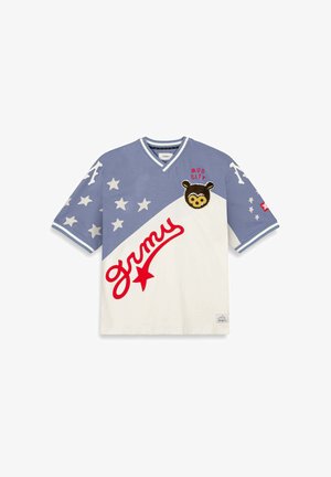 Camiseta de algodón de manga corta con un diseño de bloques de color azul y blanco, patrones de estrellas, un texto rojo "grmy" y un parche de oso etiquetado como "MUD CITY."