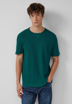 Cyaanblauw T-shirt met korte mouwen en ronde halslijn, voorzien van een subtiele textuur, gedragen met blauwe denimbroeken, met een relaxte pasvorm en strakke lijnen.