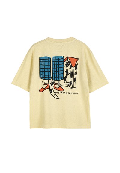 Chemise beige avec illustration d'une personne portant un pantalon à carreaux bleu et des chaussures rouges, debout à côté d'un chien dalmatien, texte « L'amitié avec un chien est pour toujours. »