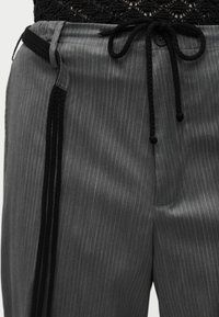 Γκρι παντελόνι με ρίγες και μαύρη πλεκτή μέση με κορδόνι, συνδυασμένο με μαύρο υφασμάτινο τοπ που είναι μπουσουρισμένο μέσα.