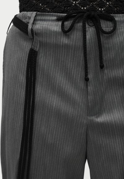 Γκρι παντελόνι με ρίγες και μαύρη πλεκτή μέση με κορδόνι, συνδυασμένο με μαύρο υφασμάτινο τοπ που είναι μπουσουρισμένο μέσα.