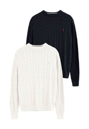 Zwei Zopfpullover, einer weiß und einer schwarz, jeweils mit kleinem gesticktem Logo auf der linken Brustseite und gerippten Bündchen und Saum.