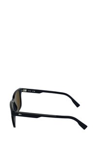 Occhiali da sole neri con finitura lucida, lenti rettangolari e montature spesse. Presentano dettagli in metallo argentato e logo inciso sulle stanghette.