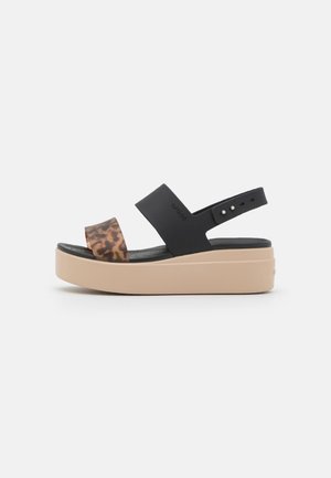 Sandale plateforme avec semelle beige, bride médiane noire et bride avant à imprimé léopard, avec bride de cheville noire réglable.