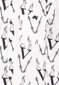 Weißes Hemd mit einem schwarzen geometrischen Muster aus Pfeilen und Stacheldraht. Enthält eine Brusttasche und schwarze Knöpfe. Glatte Stofftextur.