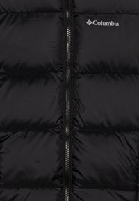 Black puffer vest featuring a zip closure down the middle. Made of smooth, shiny fabric with quilted sections and a Columbia logo on the upper right.