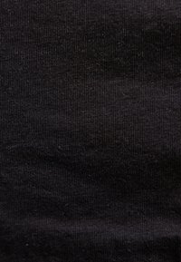 Κοντινή όψη μαύρου πλεκτού υφάσματος με ριμπ ύφανση που δείχνει τη υφή και τις λεπτές κάθετες γραμμές.