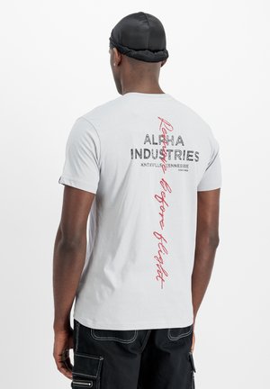 Helle graue Baumwoll-T-Shirt mit schwarzem und rotem Text auf der Rückseite, abgerundetem Saum und kurzen Ärmeln. Minimalistisches Design, keine Muster.