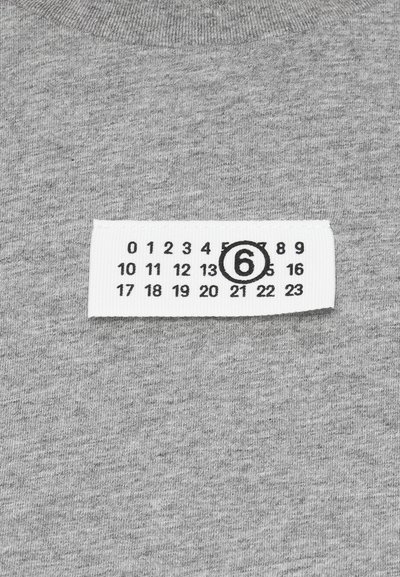 Grå bomullsstoff med en strukturert overflate som viser en hvit klesetikett med svarte tall og en sirkel rundt "6".