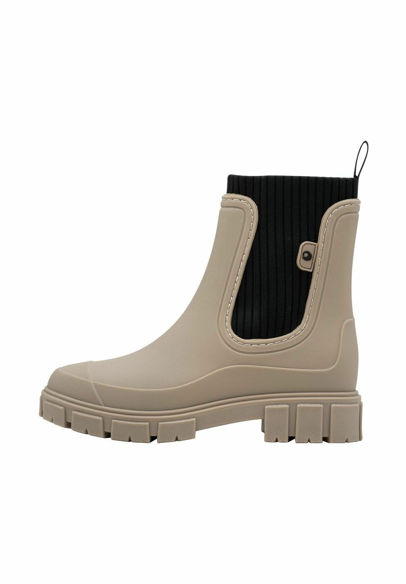 Botte chelsea en caoutchouc beige avec un dessus côtelé noir, une découpe sur le côté et une semelle texturée dotée de segments rectangulaires pour une adhérence et une stabilité accrues.