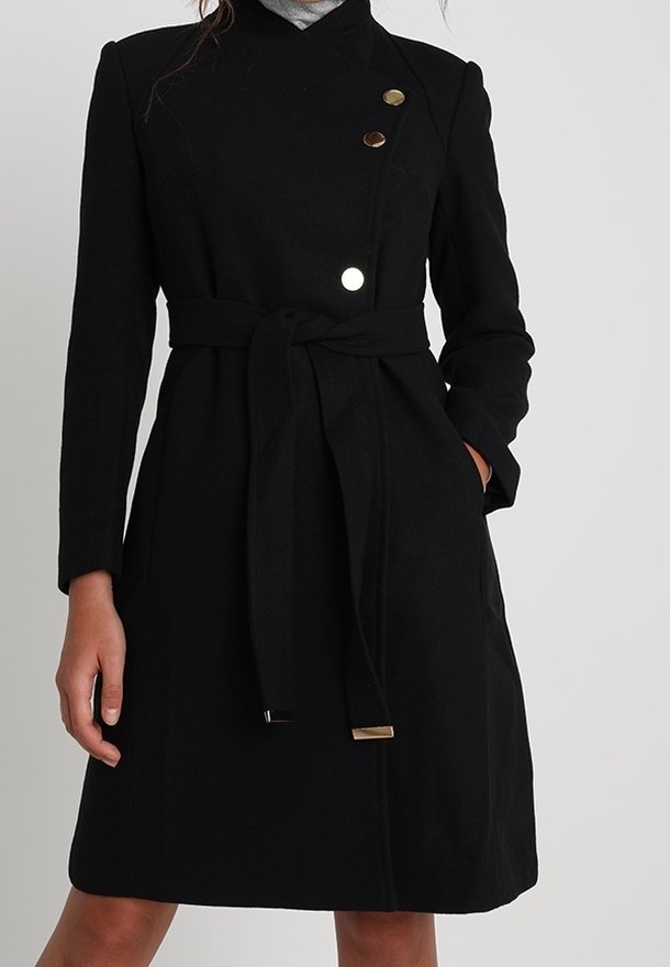 Abrigo de lana negro con diseño envolvente, tres botones en contraste, un cinturón atado en la cintura y bolsillos laterales. Textura suave, hasta la rodilla.
