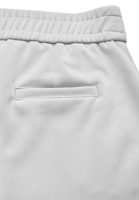 Pantalon de survêtement gris clair avec une texture lisse, doté d'une taille élastique et d'une poche arrière rectangulaire avec des bords cousus.