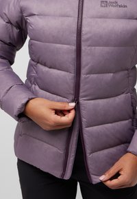 Giacca a vento viola con zip frontale, dotata di un design trapuntato, colletto alto e polsini elasticizzati. Logo inserito nella zona del petto.