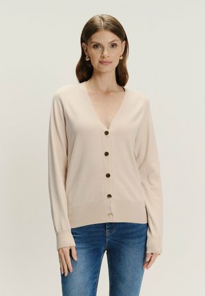 Beżowy sweter robiony na drutach z dekoltem w serek, długimi rękawami i pięcioma okrągłymi guzikami w kolorze złotym z przodu. Żebrowany dół i mankiety.