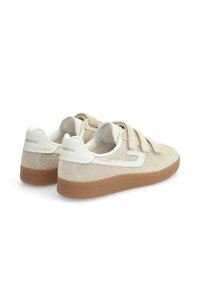 Baskets en suède beige avec des accents blancs, dotées d'un design à bande velcro et d'une semelle extérieure en caoutchouc gomme texturé.