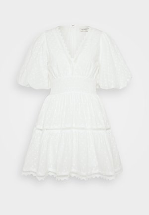 White dress with puff sleeves, smocked waist, and tiered skirt. Features textured polka dots and a decorative lace trim. V-neck design.