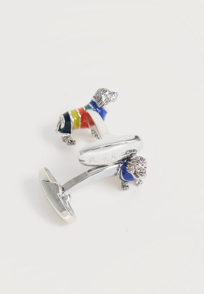 Boutons de manchette en argent en forme de chiens portant des pulls rayés bleu, jaune, rouge, vert et noir sur fond blanc.