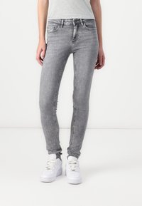 Grey skinny jeans with a faded wash, five pockets, and belt loops, paired with white sneakers. Smooth texture and slim fit.