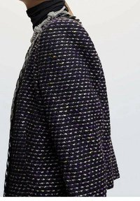 Teksturowana czarno-fioletowa tkana kurtka z metalicznymi akcentami, zdobieniami na ramionach i strukturalnym kształtem. Posiada kołnierz oraz dopasowane rękawy.