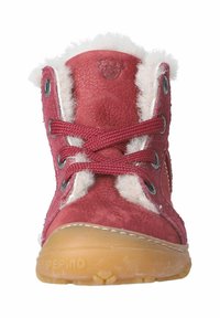 Červená kožená bota s bílým kožíškem, kulatou špičkou a černými dírkami na šněrování. Obsahuje tmavě červené tkaničky a světle hnědou gumovou podrážku.