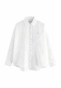 Camicia bianca a maniche lunghe in tessuto strutturato, con chiusura a bottoni frontale, colletto appuntito e taschino singolo sul petto. Dettaglio di motivo sottile.