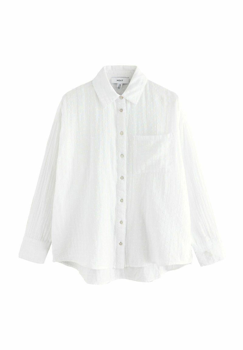 Camicia bianca a maniche lunghe in tessuto strutturato, con chiusura a bottoni frontale, colletto appuntito e taschino singolo sul petto. Dettaglio di motivo sottile.