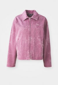 Rosa denimjakke med krage, glidelås foran, sidelommer og en falmet tekstur. Har en liten "obey"-logo på brystet.