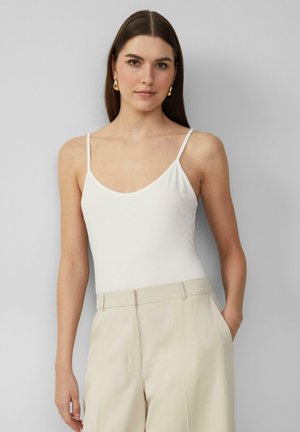 Witte spaghettiband bodysuit met een ronde hals, gemaakt van zachte stof, gecombineerd met hoge beige broeken. Eenvoudig en minimalistisch ontwerp.